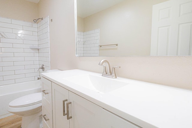 full bathroom with tiled shower / bath, vanity, wood-type flooring, and toilet