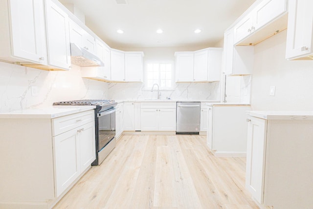 kitchen featuring sink, light hardwood / wood-style flooring, range hood, white cabinets, and appliances with stainless steel finishes