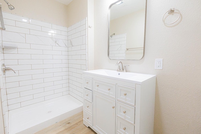 bathroom featuring hardwood / wood-style floors, vanity, and tiled shower