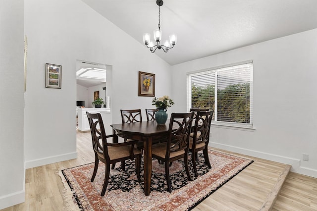 dining room with an inviting chandelier, light hardwood / wood-style flooring, and lofted ceiling