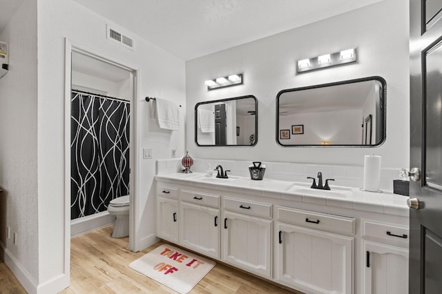 bathroom featuring hardwood / wood-style floors, vanity, toilet, and curtained shower