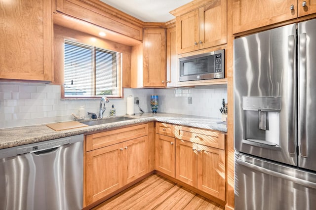 kitchen with light hardwood / wood-style flooring, sink, appliances with stainless steel finishes, and tasteful backsplash