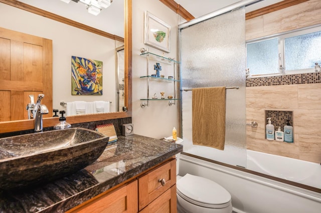 full bathroom featuring vanity, toilet, crown molding, and bath / shower combo with glass door