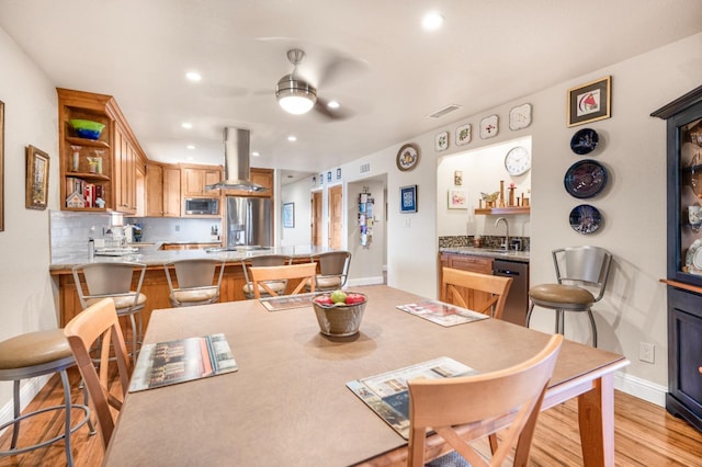 dining space with light wood-type flooring and ceiling fan