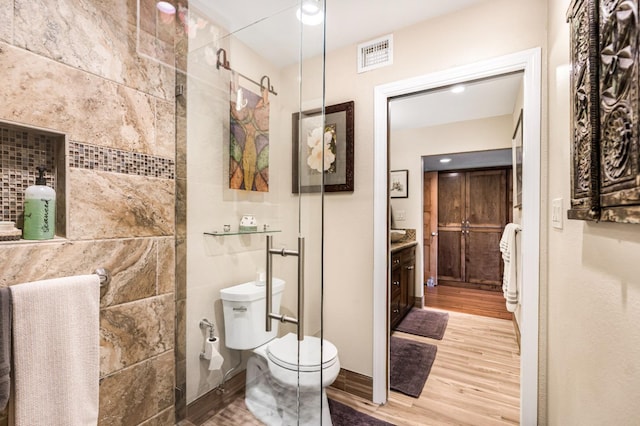 bathroom with wood-type flooring, vanity, toilet, and a shower with door