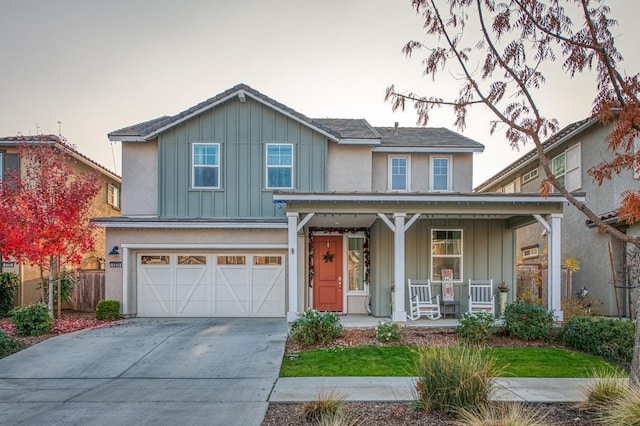 traditional home featuring board and batten siding, driveway, fence, covered porch, and a garage