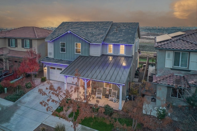 view of front of property with driveway, a garage, metal roof, board and batten siding, and a standing seam roof