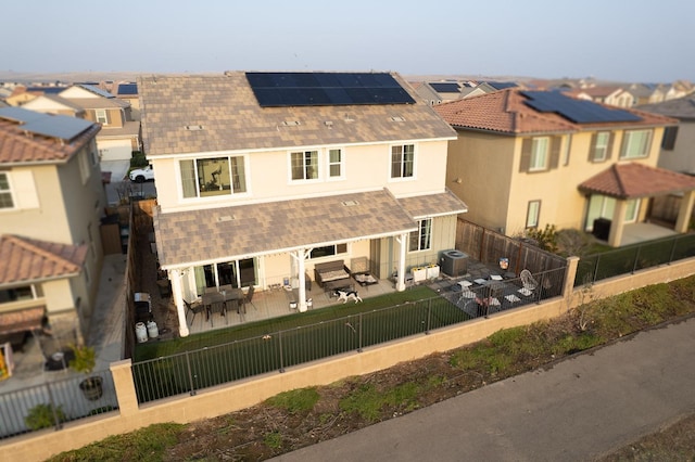 back of property featuring a patio area, a fenced backyard, solar panels, cooling unit, and a shingled roof