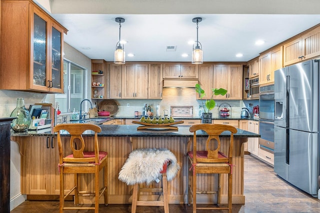 kitchen with a kitchen bar, kitchen peninsula, dark hardwood / wood-style flooring, stainless steel appliances, and sink