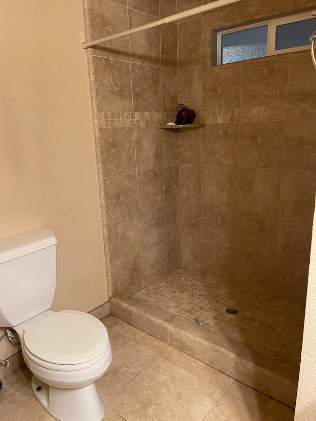 bathroom with a tile shower, tile patterned flooring, and toilet