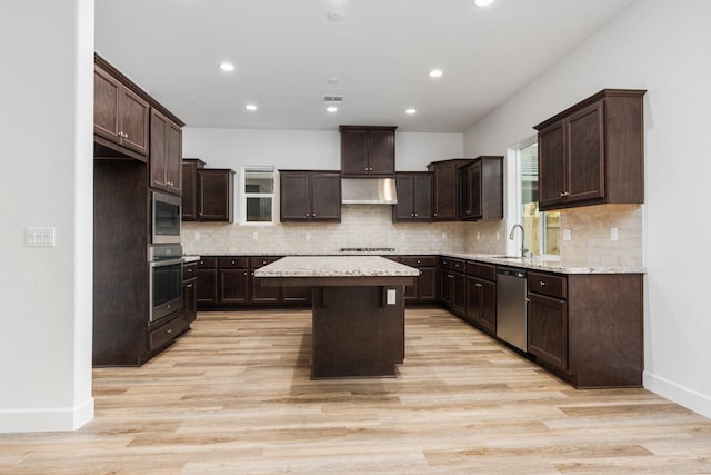 kitchen with ventilation hood, a center island, light wood-type flooring, and stainless steel appliances