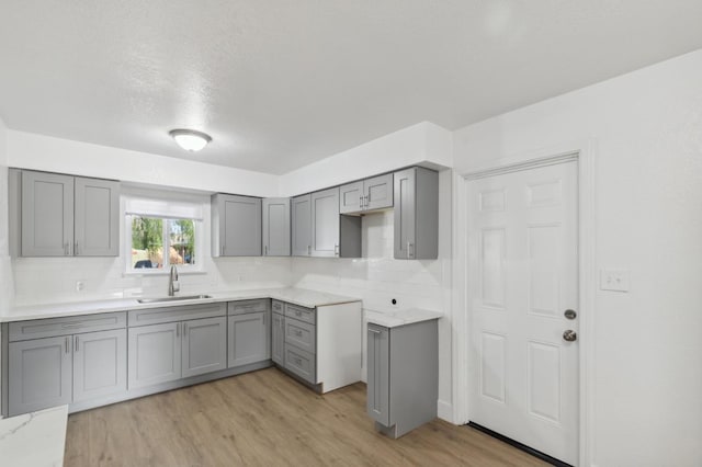 4756 E Woodward Ave, Fresno, CA 93702 - kitchen featuring backsplash, light wood finished floors, gray cabinetry, and a sink