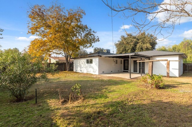 back of house with a lawn and a patio