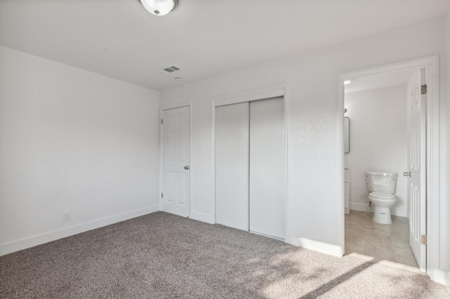 unfurnished bedroom featuring light carpet and ensuite bath