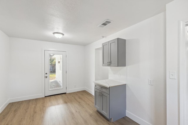 kitchen featuring a textured ceiling, light hardwood / wood-style floors, and gray cabinets