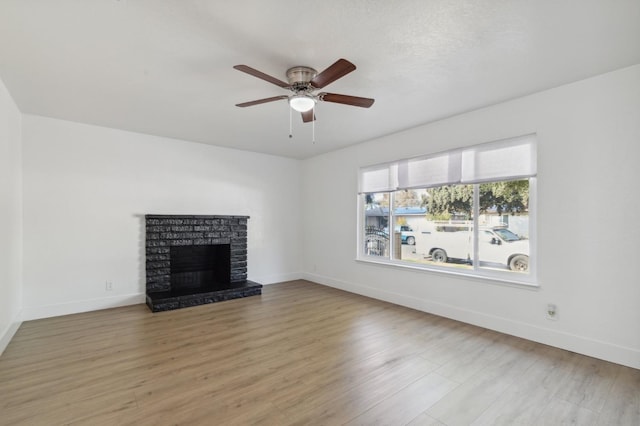 4756 E Woodward Ave, Fresno, CA 93702 - unfurnished living room with light wood finished floors, baseboards, a ceiling fan, and a brick fireplace