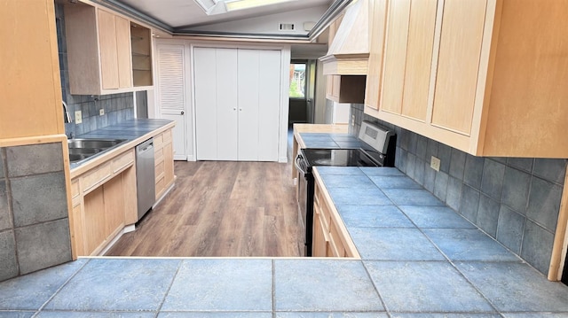 kitchen featuring stainless steel appliances, lofted ceiling, tile counters, and light brown cabinets