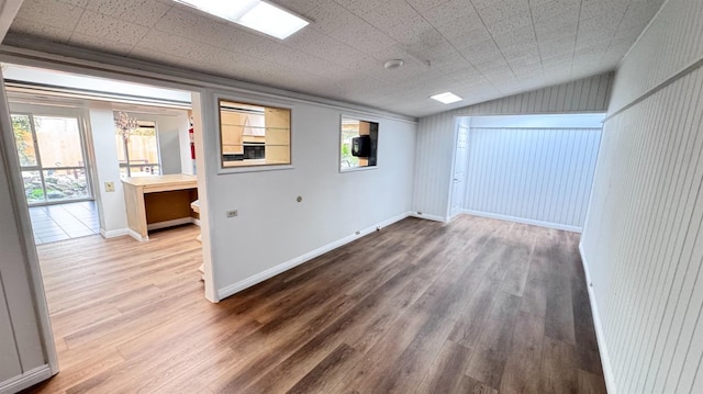 unfurnished room featuring plenty of natural light, wood-type flooring, and vaulted ceiling