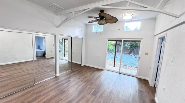 unfurnished bedroom featuring access to exterior, hardwood / wood-style floors, a high ceiling, and two closets