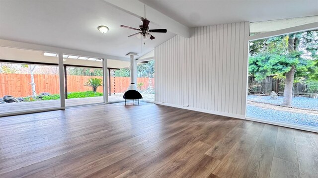 unfurnished living room with hardwood / wood-style flooring, vaulted ceiling with beams, and ceiling fan