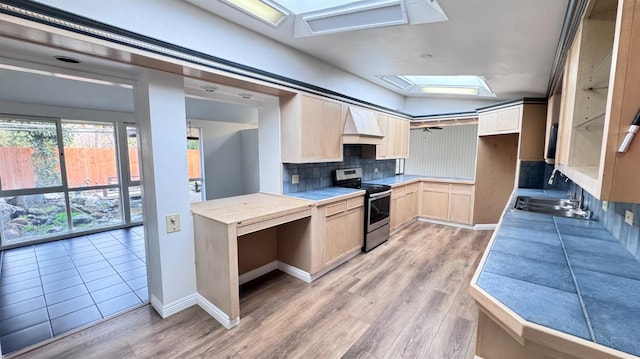 kitchen with light brown cabinetry, sink, custom exhaust hood, stainless steel range with electric stovetop, and backsplash