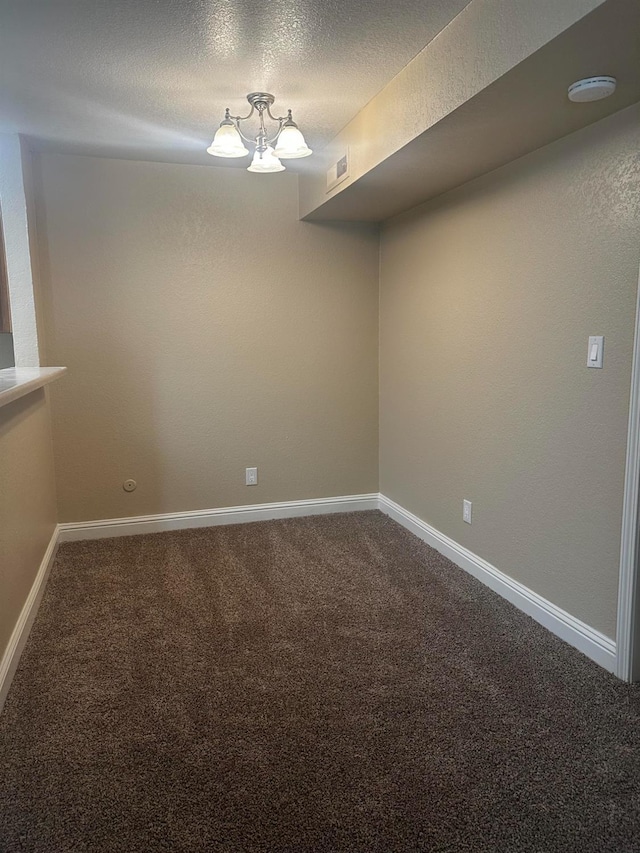 carpeted spare room with a notable chandelier and a textured ceiling