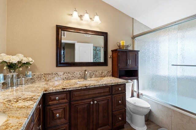 5870 E Midwick Ln, Fresno, CA 93727 - full bathroom featuring double vanity, bath / shower combo with glass door, and toilet