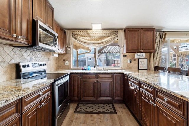 5870 E Midwick Ln, Fresno, CA 93727 - kitchen with appliances with stainless steel finishes, a sink, light wood-style floors, and decorative backsplash
