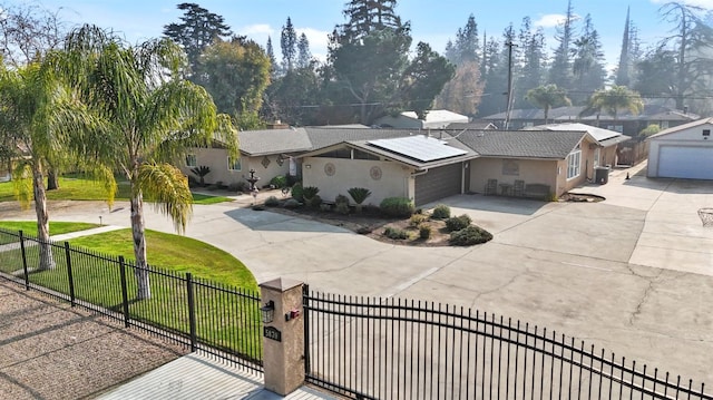 5870 E Midwick Ln, Fresno, CA 93727 - view of front of home with a fenced front yard, curved driveway, a garage, roof mounted solar panels, and stucco siding