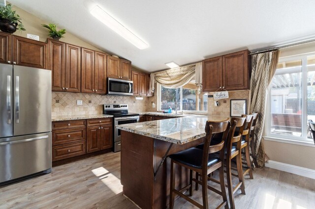 5870 E Midwick Ln, Fresno, CA 93727 - kitchen with appliances with stainless steel finishes, vaulted ceiling, light wood-style flooring, a peninsula, and tasteful backsplash