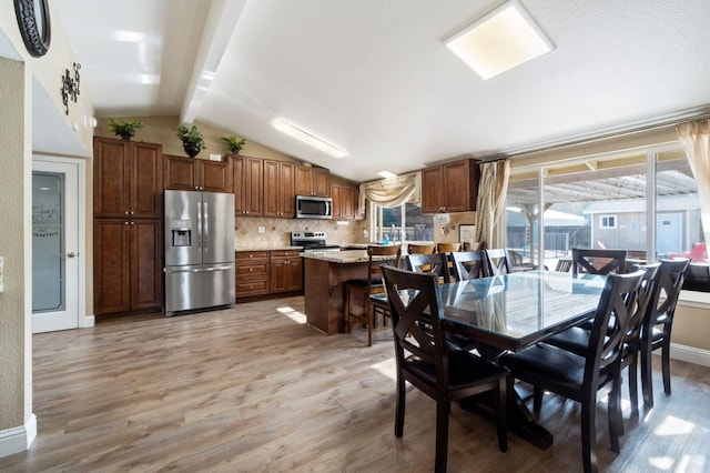 5870 E Midwick Ln, Fresno, CA 93727 - dining area with lofted ceiling, light wood-type flooring, and baseboards