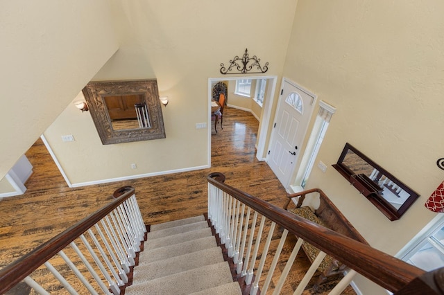 staircase featuring a towering ceiling and hardwood / wood-style flooring