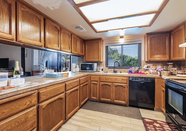 kitchen featuring tasteful backsplash, sink, tile counters, and black appliances