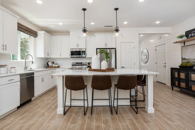 kitchen featuring stainless steel appliances, a kitchen island, and white cabinets