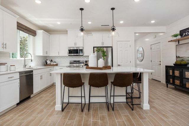 kitchen featuring a kitchen island, backsplash, appliances with stainless steel finishes, and a breakfast bar area