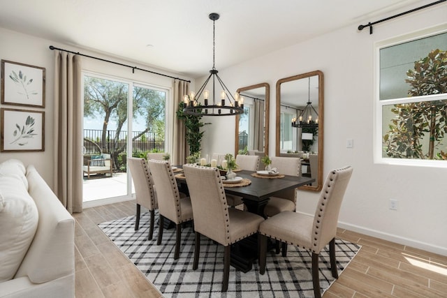 dining room with wood finish floors, baseboards, and an inviting chandelier