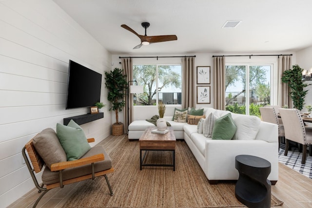 living room featuring wood finished floors, visible vents, and ceiling fan