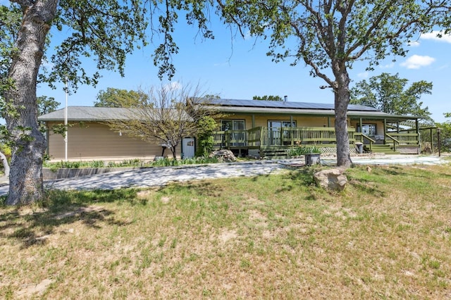 back of property with covered porch, solar panels, and a yard