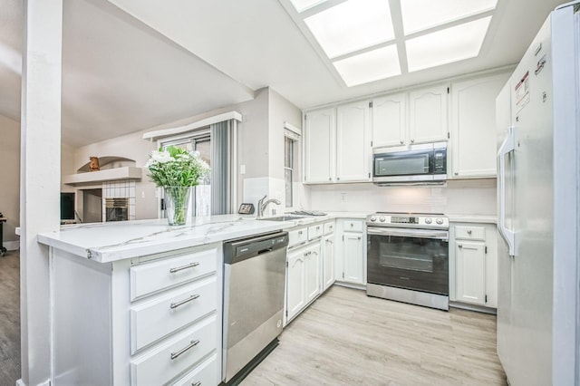 kitchen with tasteful backsplash, kitchen peninsula, white cabinetry, and stainless steel appliances