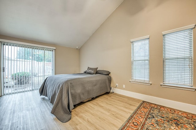 bedroom featuring access to exterior, hardwood / wood-style floors, and high vaulted ceiling