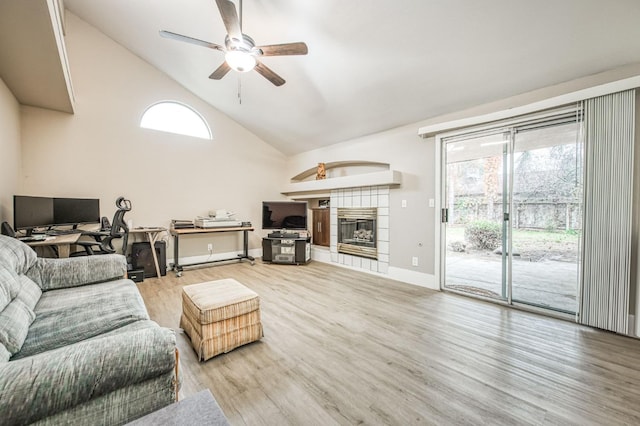 living room with ceiling fan, wood-type flooring, a wealth of natural light, and a tiled fireplace