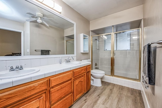 bathroom with vanity, hardwood / wood-style flooring, ceiling fan, toilet, and a shower with shower door