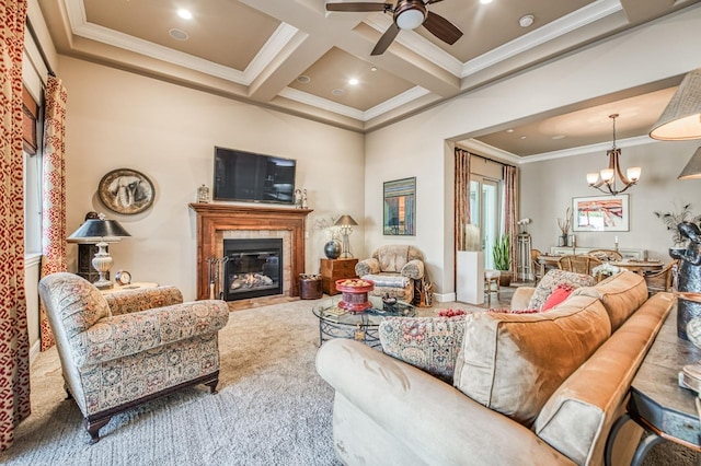 carpeted living room featuring beam ceiling, a tile fireplace, coffered ceiling, ceiling fan with notable chandelier, and ornamental molding