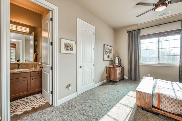 carpeted bedroom featuring connected bathroom, ceiling fan, and sink