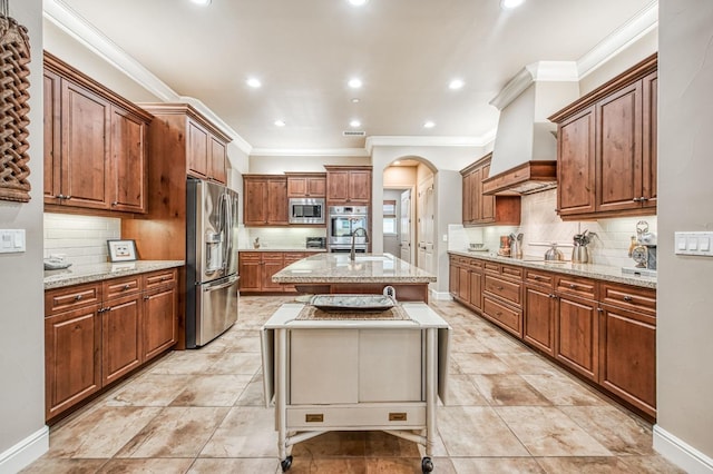 kitchen featuring a breakfast bar, a center island with sink, sink, appliances with stainless steel finishes, and custom range hood