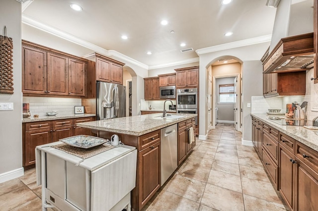 kitchen with appliances with stainless steel finishes, tasteful backsplash, ornamental molding, a kitchen island with sink, and sink