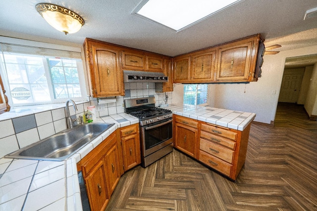 kitchen featuring sink, tile counters, tasteful backsplash, extractor fan, and stainless steel range with gas stovetop