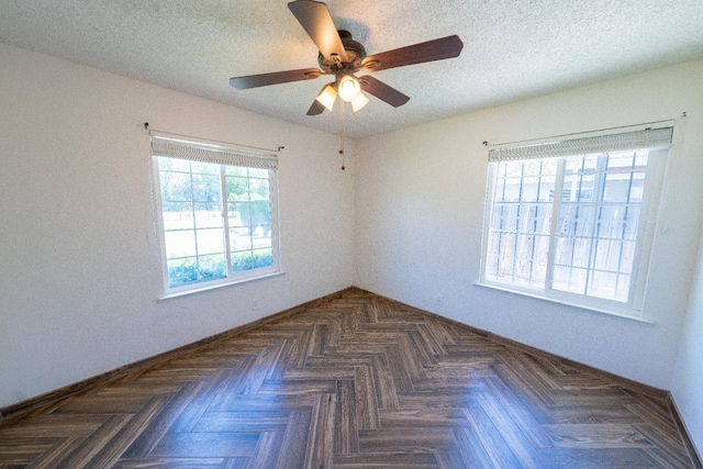 empty room with ceiling fan, dark parquet flooring, and a textured ceiling