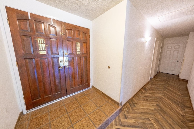 foyer featuring a textured ceiling and dark parquet floors