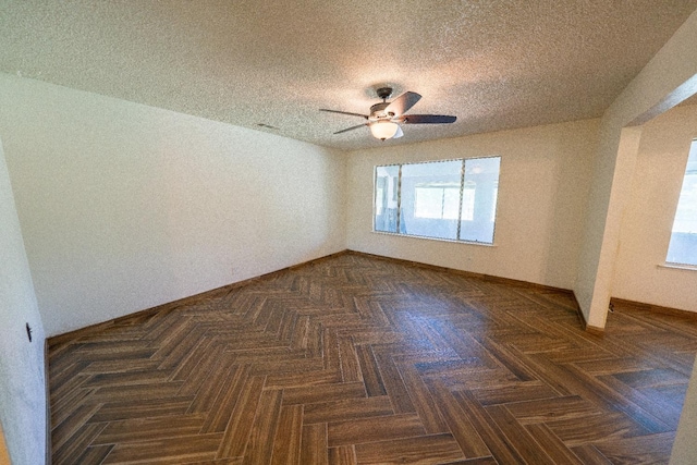 unfurnished room with ceiling fan, dark parquet floors, a healthy amount of sunlight, and a textured ceiling